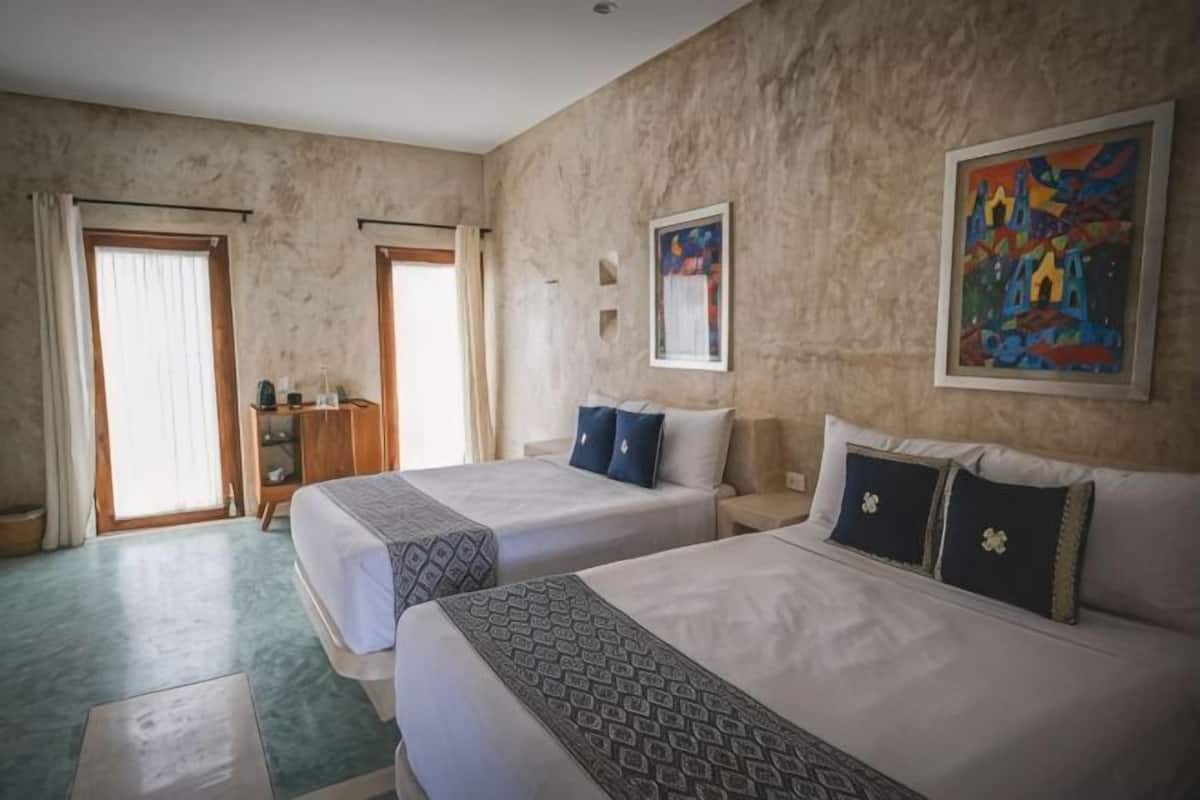 A hotel room with two beds, a wardrobe, a painting, and a door leading to a balcony.