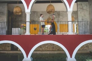 A balcony with a railing, a person standing, and another person sitting. - Wakax Hacienda - Cenote & Boutique Hotel (Tulum)
