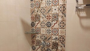 Ein Duschbereich mit einer gefliesten Wand mit geometrischem Muster.