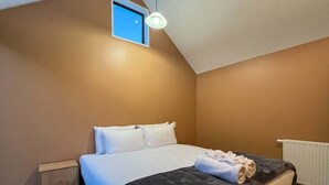 A bedroom with a bed, a nightstand, a window, and a ceiling light. - Queenstown Family Base, 100m to the Lake (Queenstown)