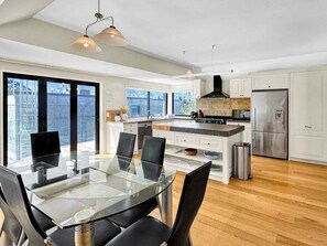 A modern kitchen with a glass dining table, black chairs, and a stainless steel refrigerator. - Queenstown Family Base, 100m to the Lake (Queenstown)
