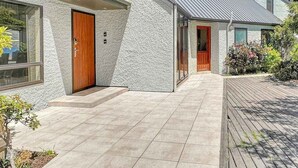 A modern house with a stone facade, a wooden front door, and a paved driveway. - Queenstown Family Base, 100m to the Lake (Queenstown)