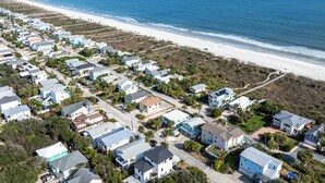 Vue aérienne d’une zone résidentielle côtière, avec des maisons, une plage et l’océan.