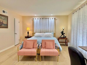 A bedroom with a bed, two pink chairs, a desk, a lamp, and a painting on the wall. - Spacious 4BR Dallas Home near Love Field Airport (Dallas)