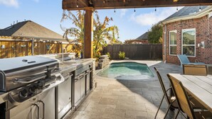 Un jardin avec un barbecue, une piscine et un espace salon extérieur.