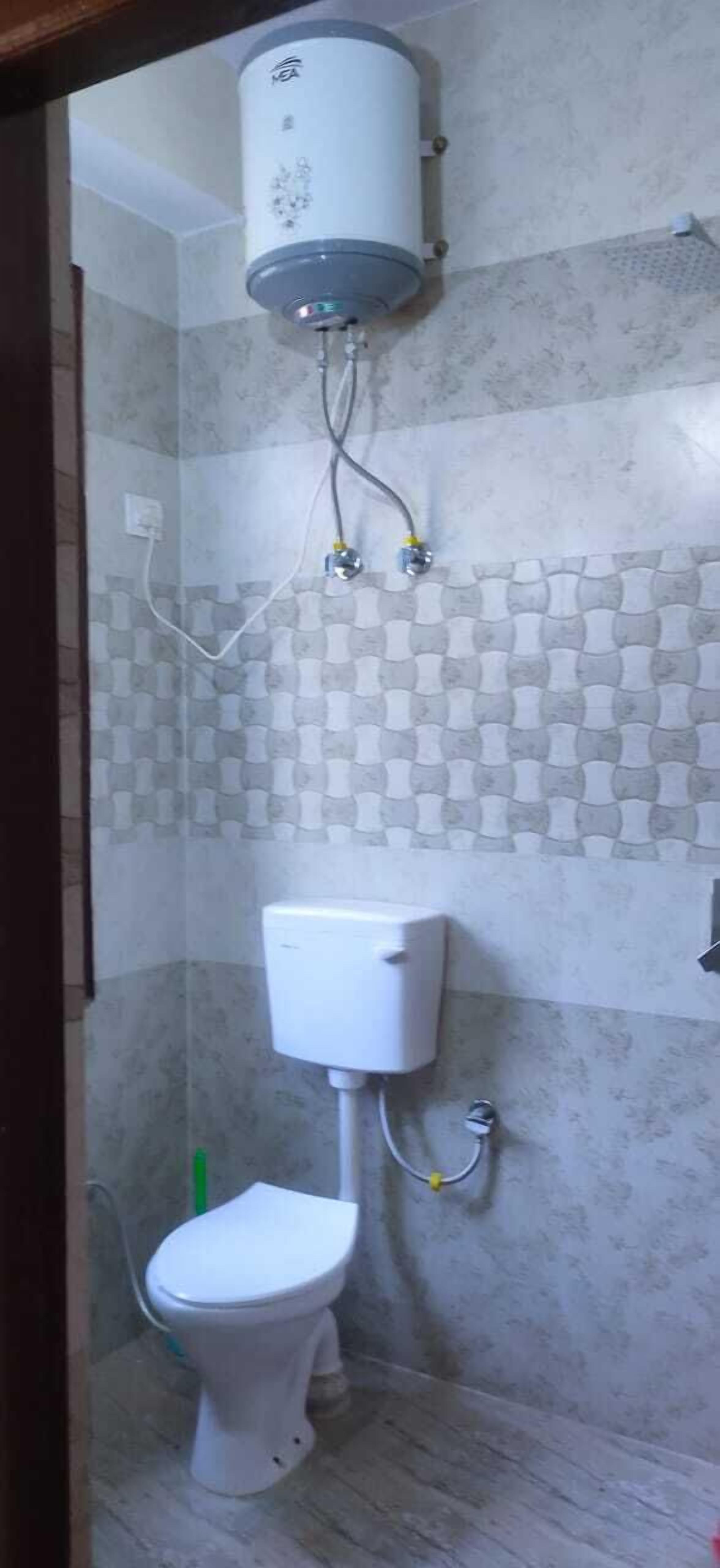 A bathroom with a toilet, a shower, and a water heater.