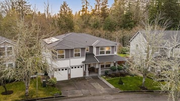 A two-story house with a garage, surrounded by trees and a well-maintained lawn.