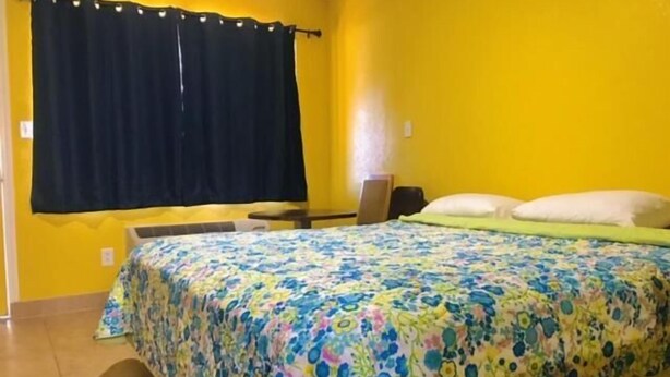 A room with a bed, a desk, and a window with curtains. - Commodore motel (Oakland)