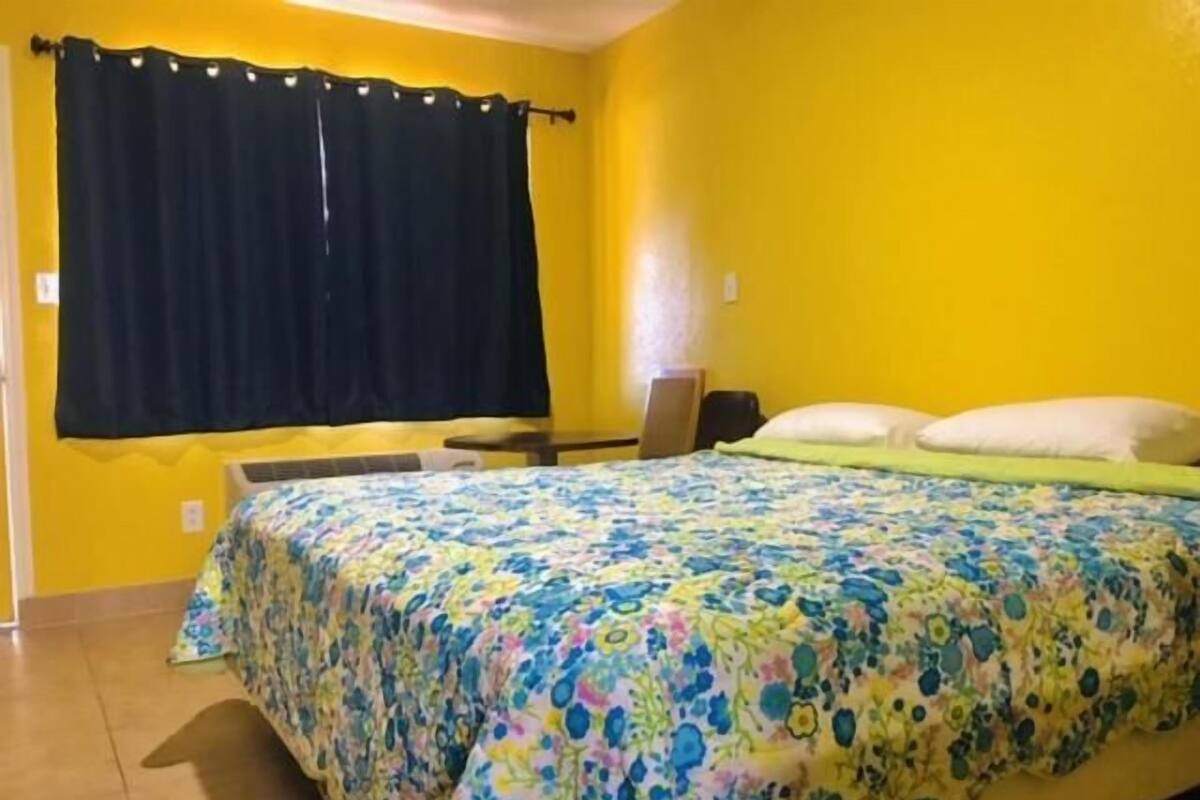 A room with a bed, a desk, and a window with curtains.