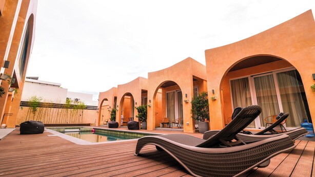 A poolside area with lounge chairs, a pool, and arched walkways. - Villa Sorrento by SMS Hospitality (San Antonio)