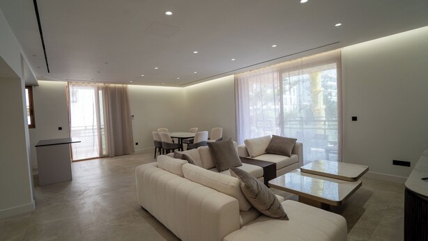 A modern living room with a sofa set, a coffee table, and a dining area with chairs. - Elegant Glyfada Residence • 2BR Master • High-End Finishes • Prime Location (Glifada)