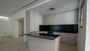 A modern kitchen with white cabinets and a black countertop. - Elegant Glyfada Residence • 2BR Master • High-End Finishes • Prime Location (Glifada)