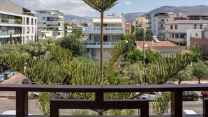 A balcony with a view of a residential area, including buildings and a mountain in the background. - Elegant Glyfada Residence • 2BR Master • High-End Finishes • Prime Location (Glifada)