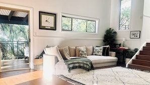 Un salon avec un canapé, un tapis à motifs et un escalier.