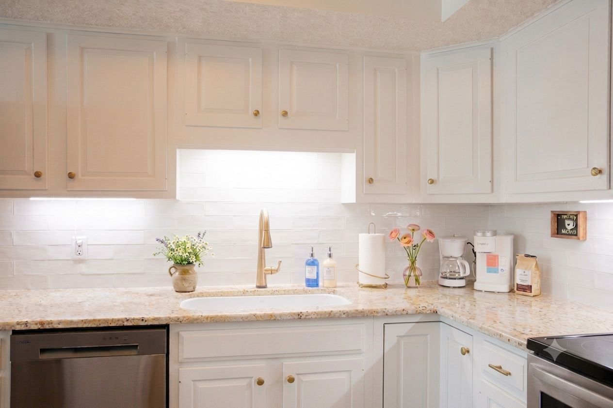 A kitchen with white cabinets, a granite countertop, a dishwasher, and a coffee maker.