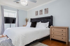 A bedroom with a large bed, a bedside table, a ceiling fan, and decorative wall art. - HOA Townhouse in wonderful High Point by the Lake (High Point)
