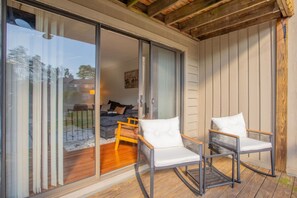 A modern outdoor seating area with two white cushioned chairs and a wooden table. - HOA Townhouse in wonderful High Point by the Lake (High Point)