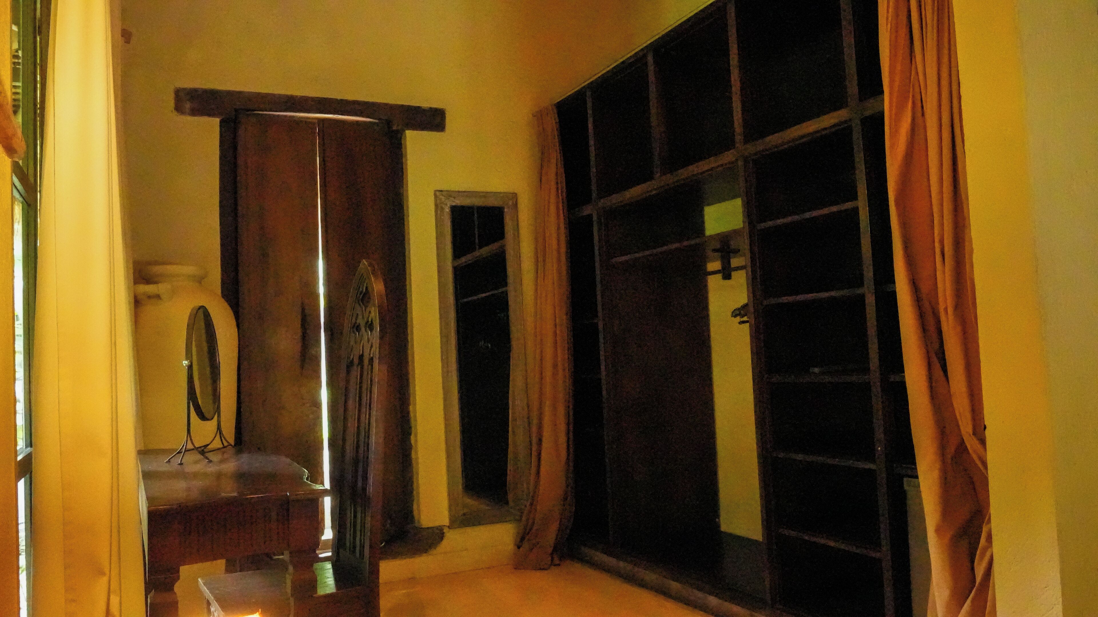 Una habitación con un ventanal grande, un espejo y un armario de madera.
