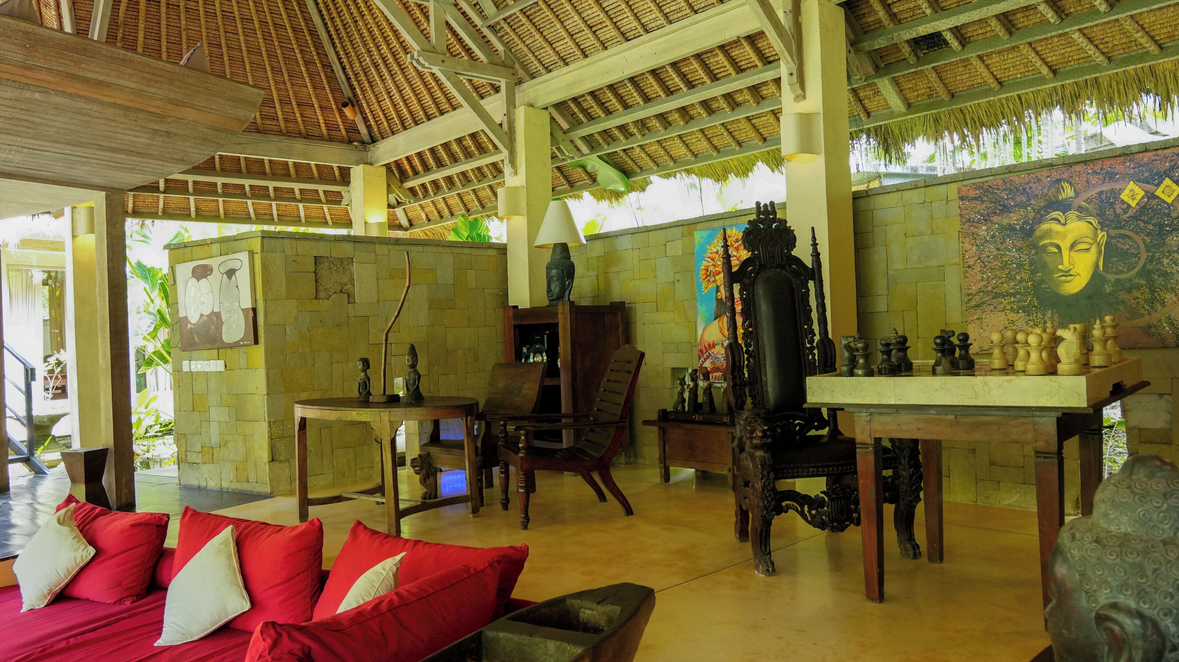 A traditional room with a thatched roof, wooden furniture, and a chessboard.