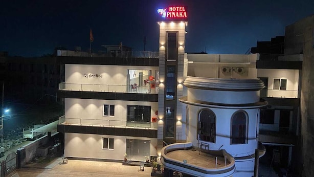 A hotel with a prominent sign, multiple floors, and a central courtyard. - Hotel Pinaka (Pratapgarh)