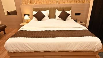 A neatly made bed with a headboard, a bedside lamp, and a nightstand with a phone and a cup.
