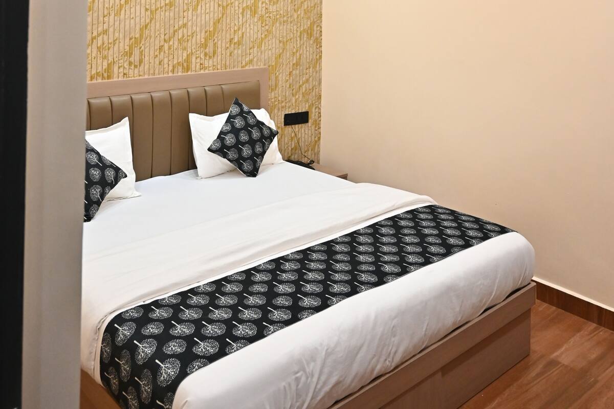 A modern bedroom with a bed, a ceiling fan, recessed lighting, and an air conditioning unit.
