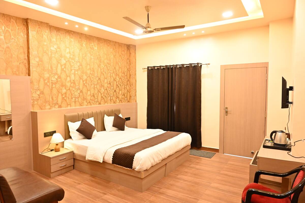 A modern hotel room with a bed, a desk with a chair, a television, and a ceiling fan.