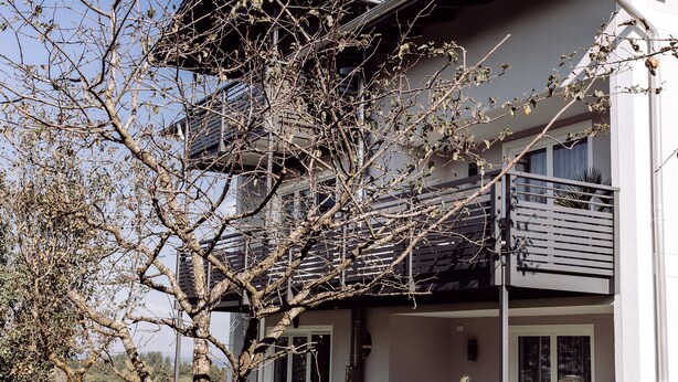 Una moderna casa a due piani con un balcone, un camino e un prato curato.