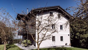 Una casa moderna a due piani con un balcone, un portico coperto e un prato curato.