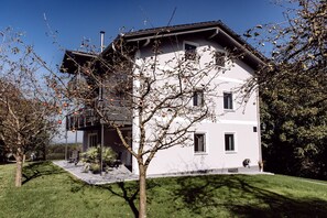 A modern two-story house with a balcony, a covered porch, and a well-maintained lawn. - Vacation apartment 1 Sonnenblick on the first floor with 2 terraces and garden (Riedering)