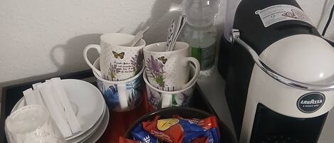 A kitchen counter with a coffee maker, a water bottle, and various kitchen items like cups, plates, and napkins.