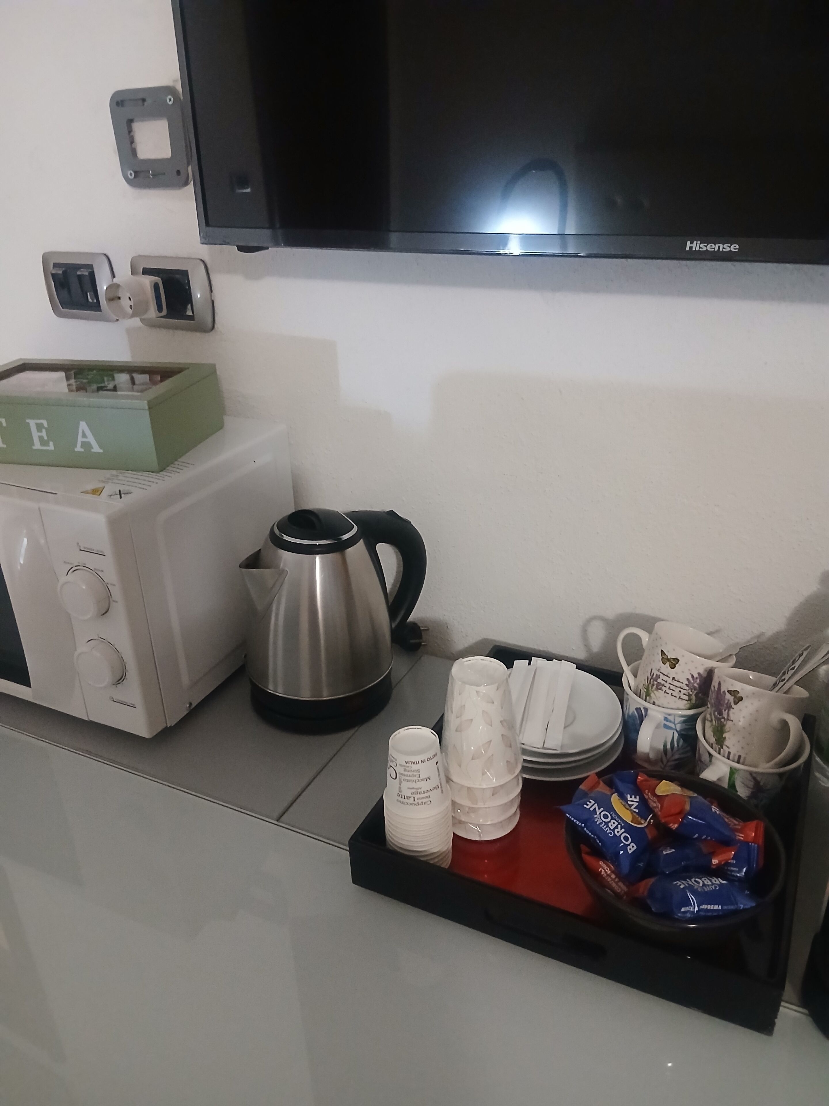 A kitchenette with a toaster, kettle, and tea box.