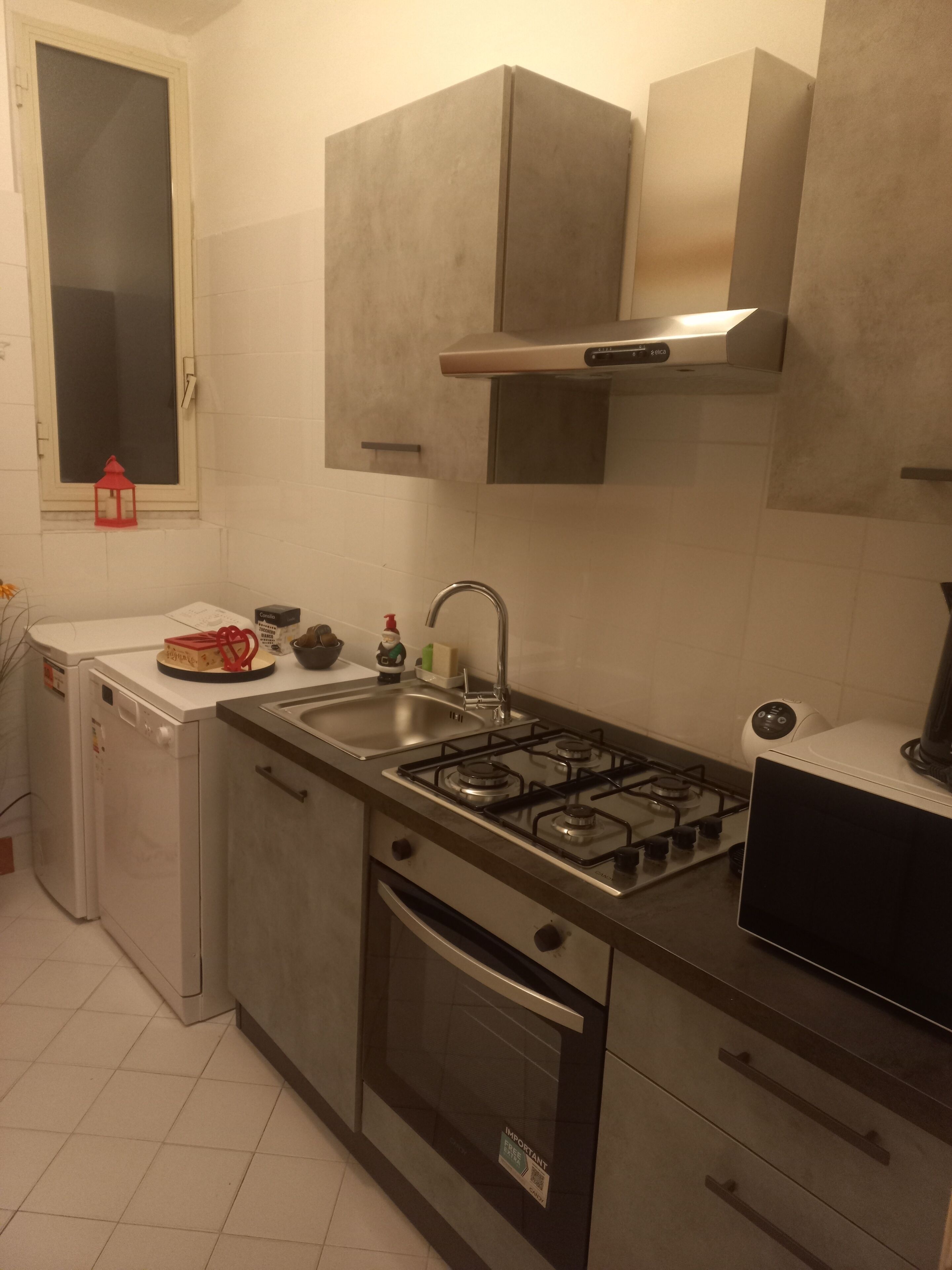A compact kitchen with a gas stove, stainless steel appliances, and white cabinetry.