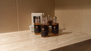 Ein Badezimmer mit Marmorplatte und drei Flaschen für Haar- und Körpershampoo.