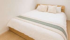 Un dormitorio con cama, cabecero de madera y ventana con persianas.