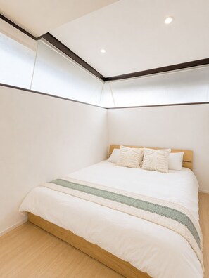 Ein Schlafzimmer mit Bett, Holz-Kopfteil und einem Fenster mit Jalousien.