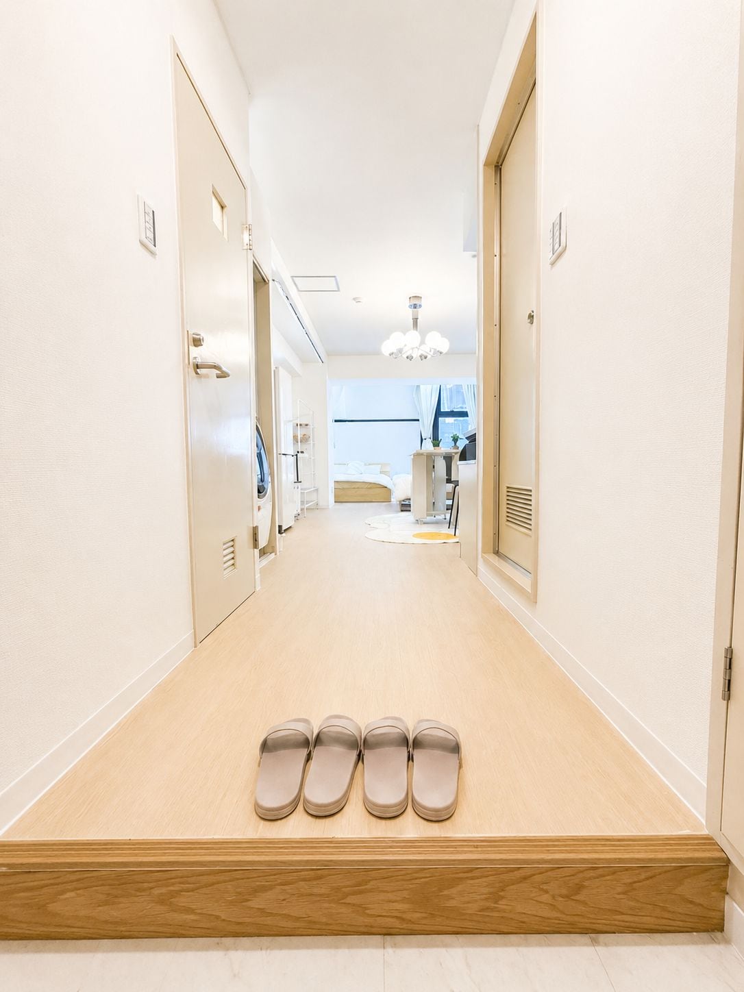 A hotel corridor with a wooden floor, a row of doors on the left, and a row of shoes on the right.