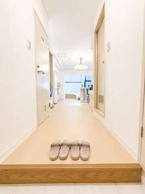 A hotel corridor with a wooden floor, a row of doors on the left, and a row of shoes on the right. - Near Shinjuku , Shibuya Area , 6 Guests , Family Stay (渋谷区)