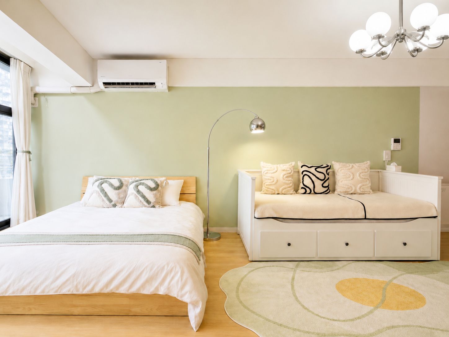 A bedroom with a bed, a sofa, an air conditioning unit, a floor lamp, and a rug.
