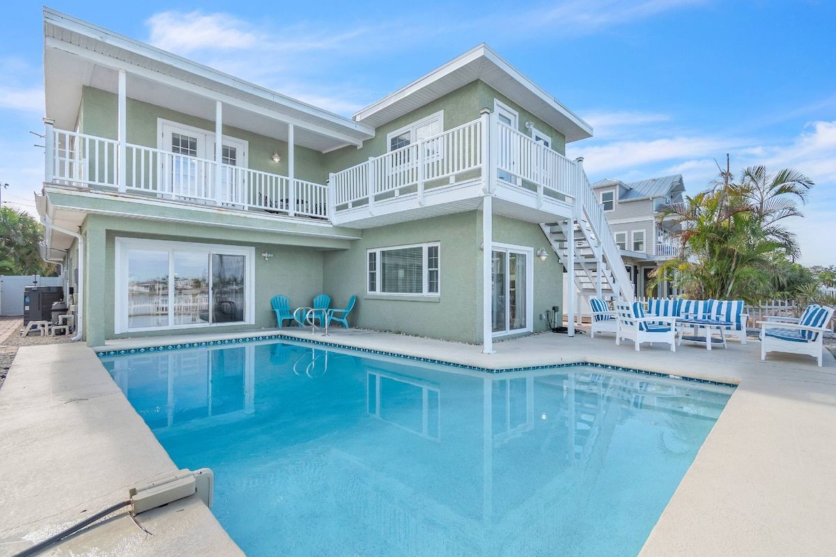 A two-story building with a swimming pool, outdoor seating, and a staircase leading to the upper level.