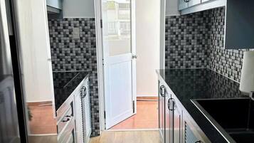 Een koelkast, een magnetron, een kookplaat, kookgerei, borden en bestek