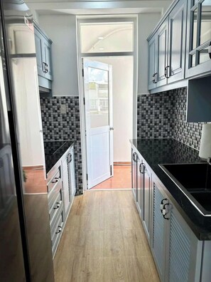 Een koelkast, een magnetron, een kookplaat, kookgerei, borden en bestek