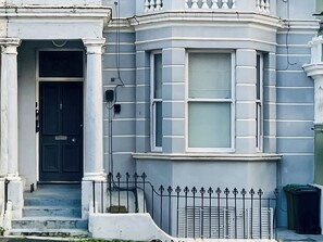 A corner building with a black door, white columns, and a black metal fence. - Modern coastal escape, 2 minutes from the beach, cafés and bars. (St. Leonards-on-Sea)