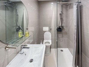 A modern bathroom with a glass shower enclosure, a white sink, and a toilet. - Modern coastal escape, 2 minutes from the beach, cafés and bars. (St. Leonards-on-Sea)