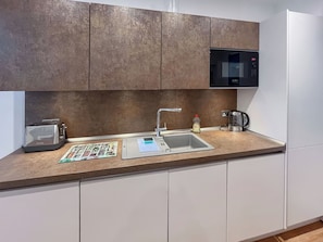 A kitchen with a toaster, sink, coffee maker, and a microwave. - Modern coastal escape, 2 minutes from the beach, cafés and bars. (St. Leonards-on-Sea)