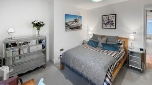 A bedroom with a bed, bedside tables, a dresser, and a mirror. - Modern coastal escape, 2 minutes from the beach, cafés and bars. (St. Leonards-on-Sea)