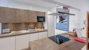 Een moderne keuken met een ingebouwde magnetron, koffiezetapparaat en broodrooster.