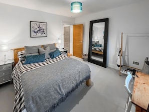 A bedroom with a bed, bedside table, lamp, and a mirror. - Modern coastal escape, 2 minutes from the beach, cafés and bars. (St. Leonards-on-Sea)