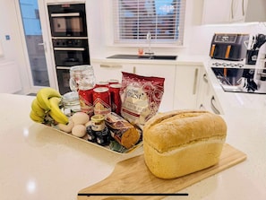 A kitchen counter with a loaf of bread, bananas, eggs, canned drinks, and a bag of crisps. - Royal Border Retreat (Berwick Upon Tweed)