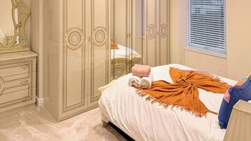 A bedroom with a bed, a dresser, a mirror, and a window with blinds.